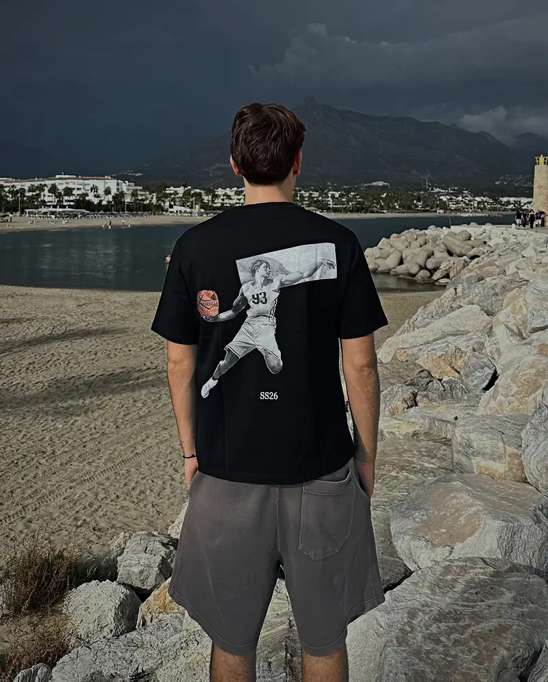 The Basketball tee, worn and seen from the back on the breakwater at Puerto Banús, with La Concha behind