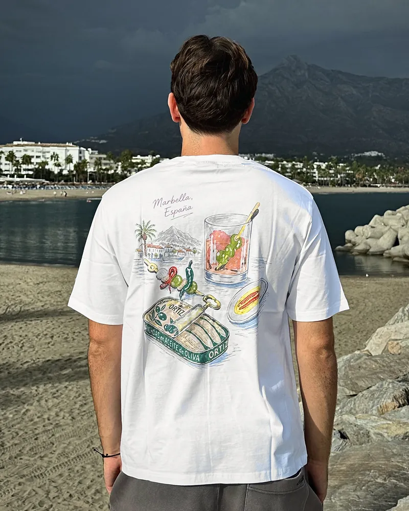 Aceitunas in white, worn, seen from the back on the beach at Puerto Banús