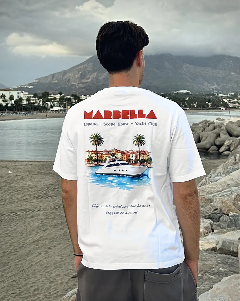 Orange Marbella text yacht in white, worn, seen from the back on the beach at Puerto Banús